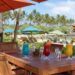 Wooden dining table with Hawaiian cocktails and beach chairs under umbrellas at The Beach House Restaurant, Turtle Bay, Oahu.