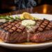 Juicy grilled steak topped with melting herb butter, served with asparagus and lemon garnish at a steakhouse.