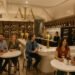 Groups of friends enjoying wine at AJA Vineyards Tasting Room in Santa Monica, with bottles displayed on shelves.
