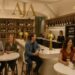 Groups of friends enjoying wine at AJA Vineyards Tasting Room in Santa Monica, with bottles displayed on shelves.