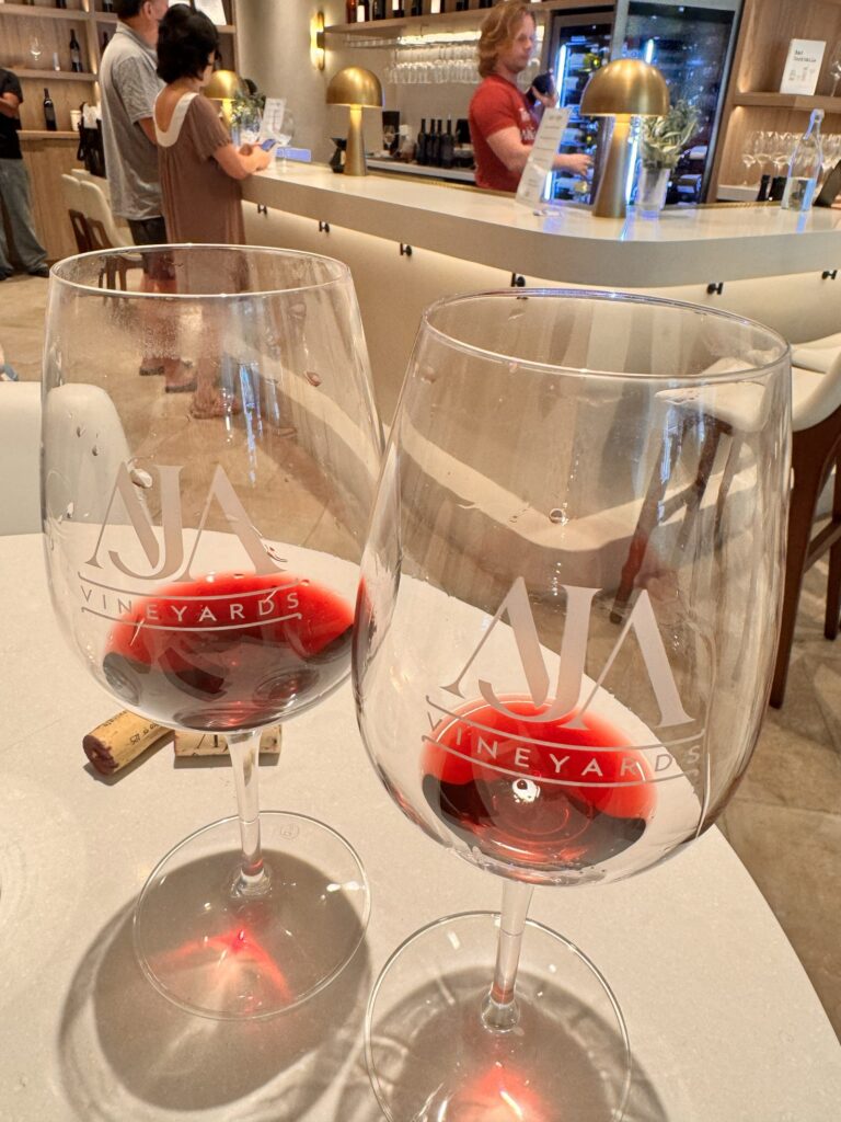 Two glasses of red wine etched with the AJA Vineyards logo, poured during a tasting flight at the Santa Monica tasting room