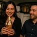 Couple on a Waymo date night sharing a chimney cone ice cream outside AJA Vineyards Tasting Room in Santa Monica.