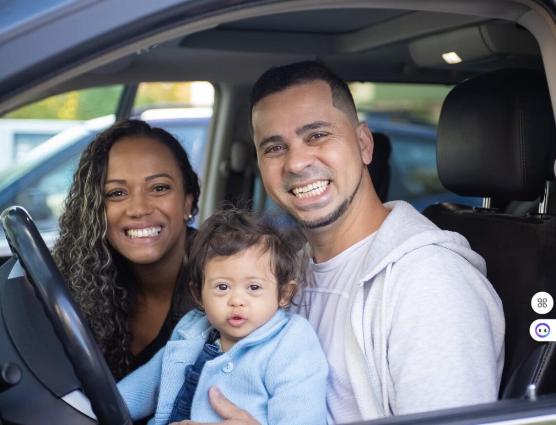 A smiling family with a young child sitting inside a car, representing a family rideshare trip.