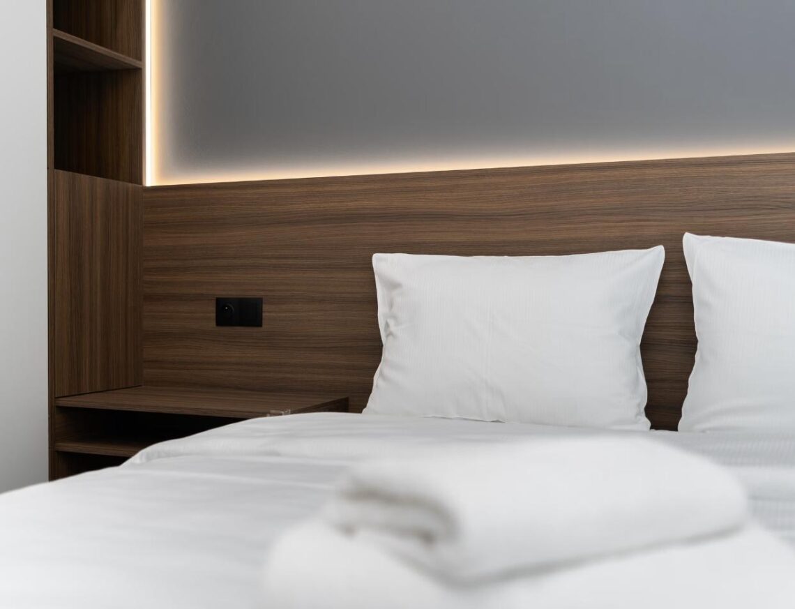 A crisp, freshly made bed with plush white pillows in a modern luxury hotel room.