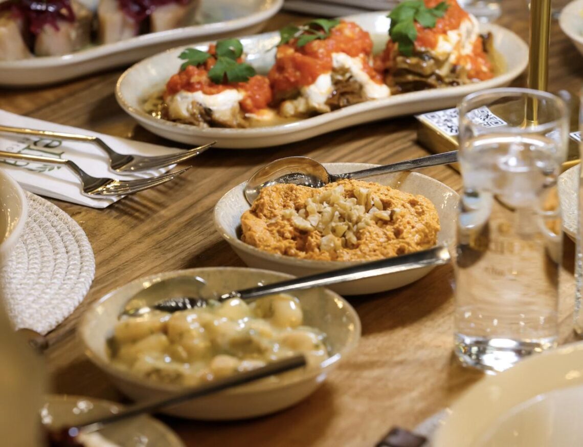 A Mediterranean mezze spread of small plates including hummus, dips, and vegetable dishes on a restaurant table.