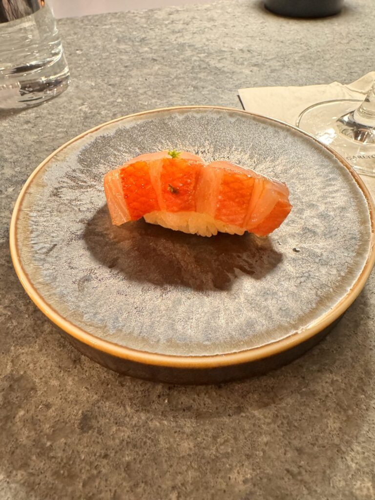 Seasonal nigiri on a speckled ceramic plate at the TAIKUN counter