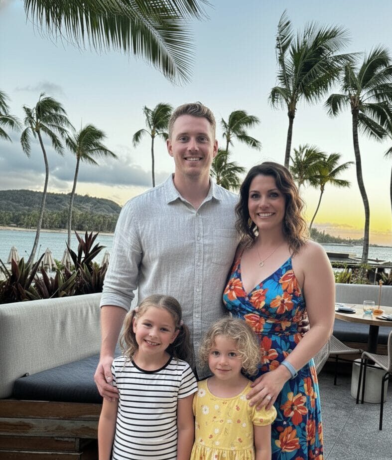 The Graham family—Ginger, Brad, Madeleine, and Charlotte—standing on a tropical resort patio at sunset, creators of the Culinary Passages family travel blog.