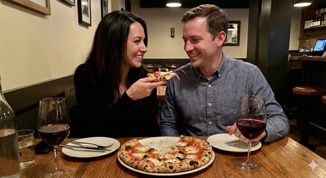 Ginger Graham feeding Brad Graham a slice of pizza in a restaurant.