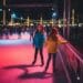 Two young girls ice skating at the Fontainebleau Las Vegas seasonal outdoor rink on the pool deck at night.