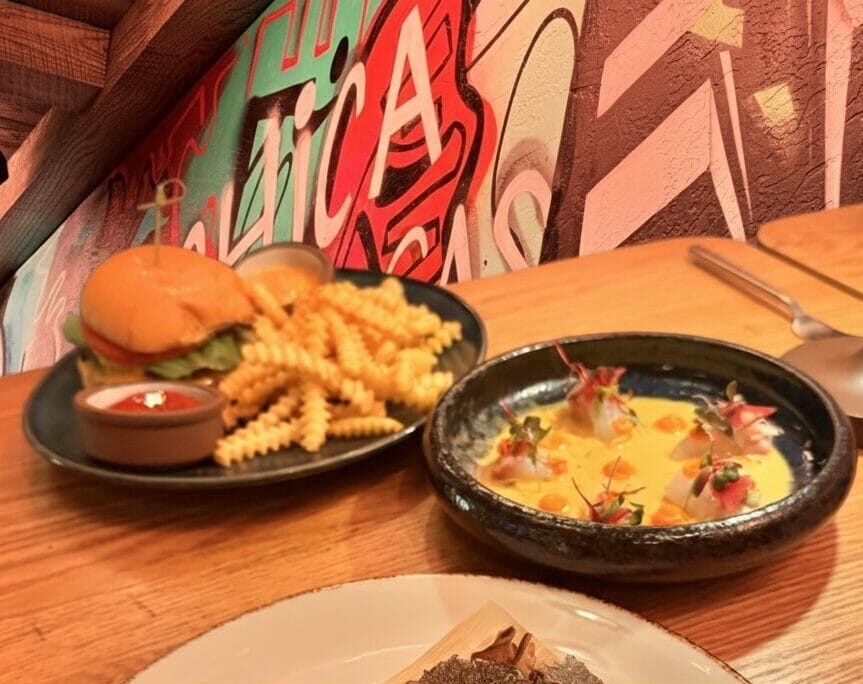 A promotional graphic for a Venetian food guide featuring a wild mushroom tamale, an ahi tuna appetizer, and a burger with fries. Text overlay reads "How to Conquer the Venetian Food Scene Without Losing Your Mind.