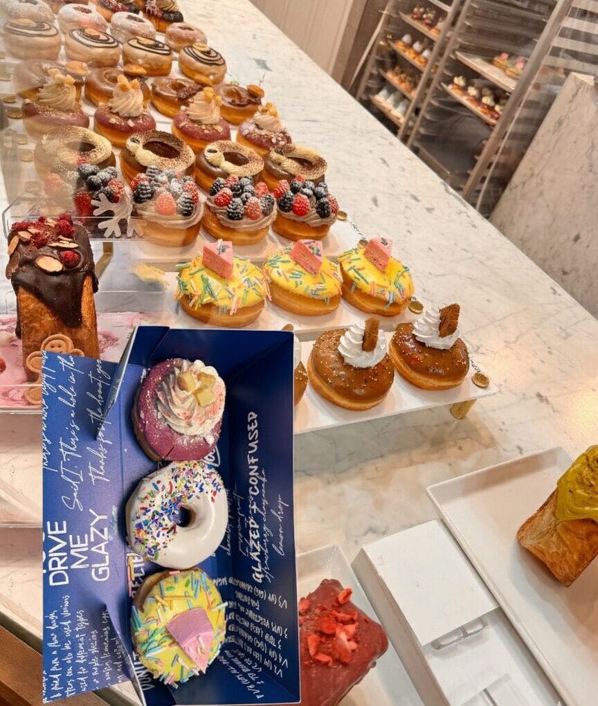 A vibrant display of luxury donuts and cruffins at Donutique in The Venetian Las Vegas, featuring gold-leaf accents, fresh berries, and artisan glazes on a marble counter.