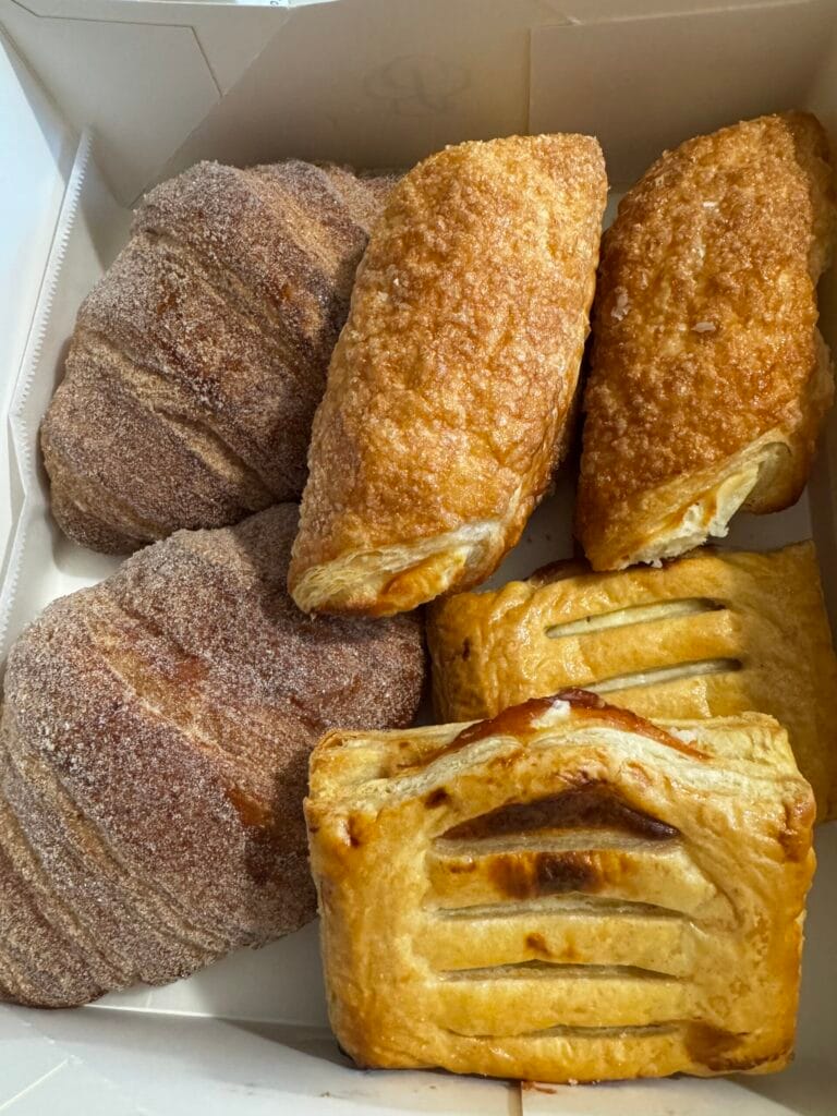 An overhead view of a Porto’s white pastry box filled with sugar-dusted guava and cheese strudels (Refugiados) 