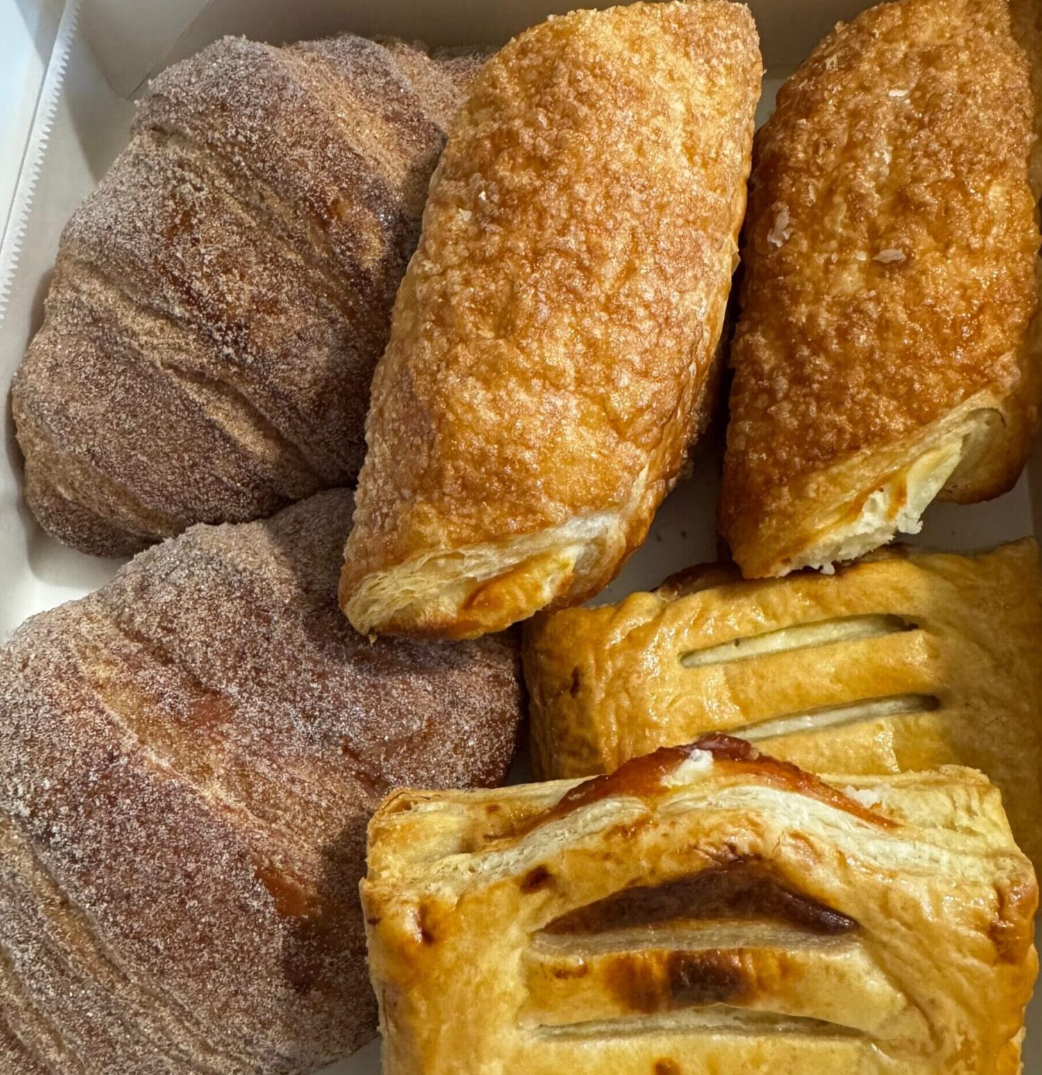 An overhead view of a Porto's white pastry box filled with sugar-dusted guava and cheese strudels (Refugiados)