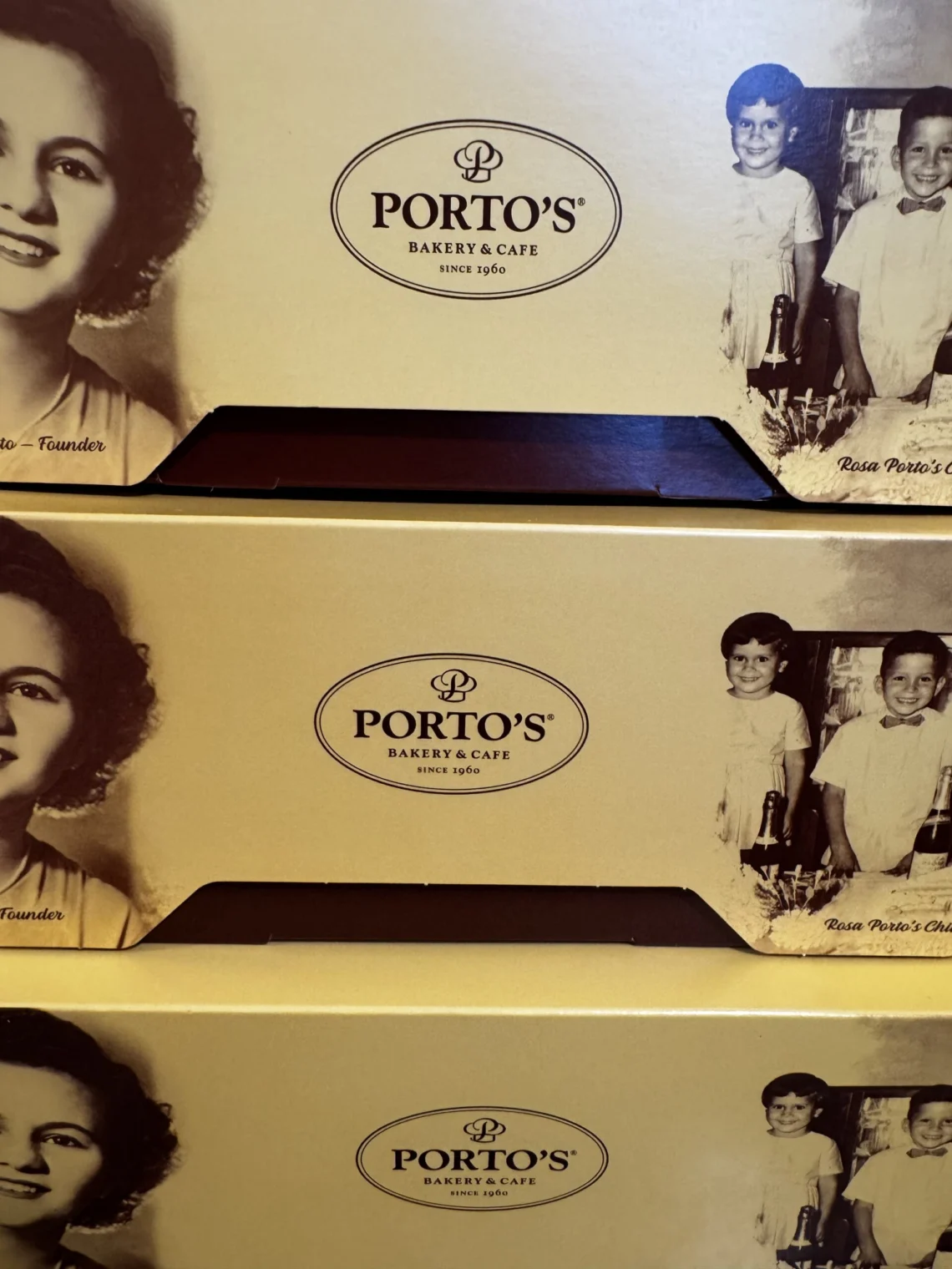 Close-up of yellow Porto’s Bakery & Cafe boxes featuring a vintage black and white portrait of founder Rosa Porto and her children.