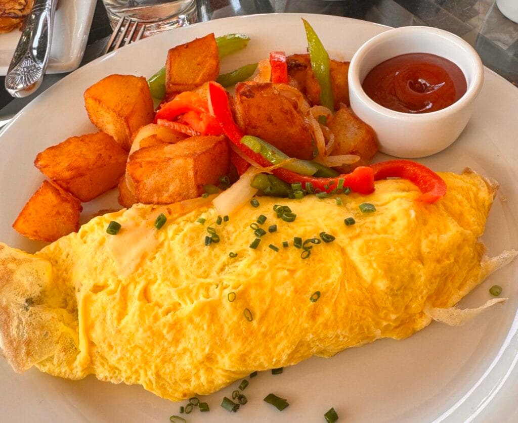 Weekend brunch at Perch LA in Downtown Los Angeles featuring a classic French omelet with breakfast potatoes and sautéed vegetables.