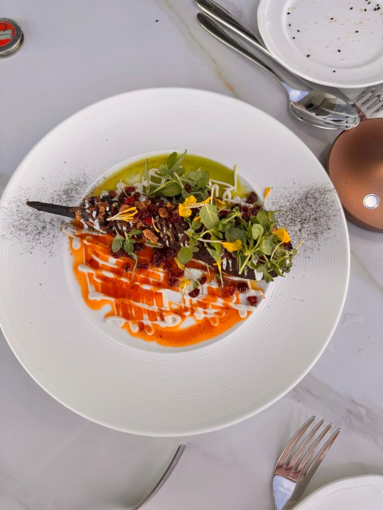 A vibrant fine-dining presentation of smoked eggplant topped with fermented whey, barberries, and fresh microgreens on a white plate at Perse Restaurant.