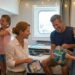 Ginger Graham and her husband Brad help their daughters Madeline and Charlotte unpack in a cruise ship cabin, featuring organized toiletries and cruise essentials.