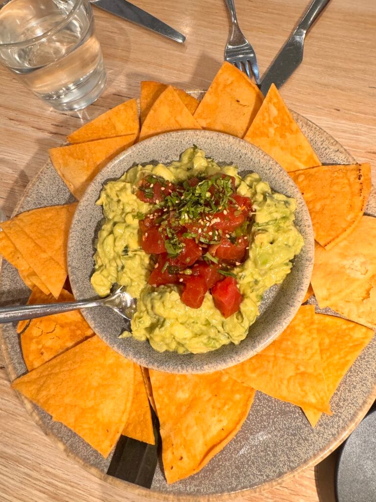 A close-up of a Guaca-Poke appetizer with fresh ahi tuna poke and guacamole served with crispy tortilla chips at Pacific Catch Santa Monica.