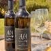 Two bottles of AJA Vineyards 2011 Proprietary Red Wine sitting on a rustic wooden wine barrel alongside etched AJA wine glasses and a small plate of crackers and cheese at the Agoura estate.
