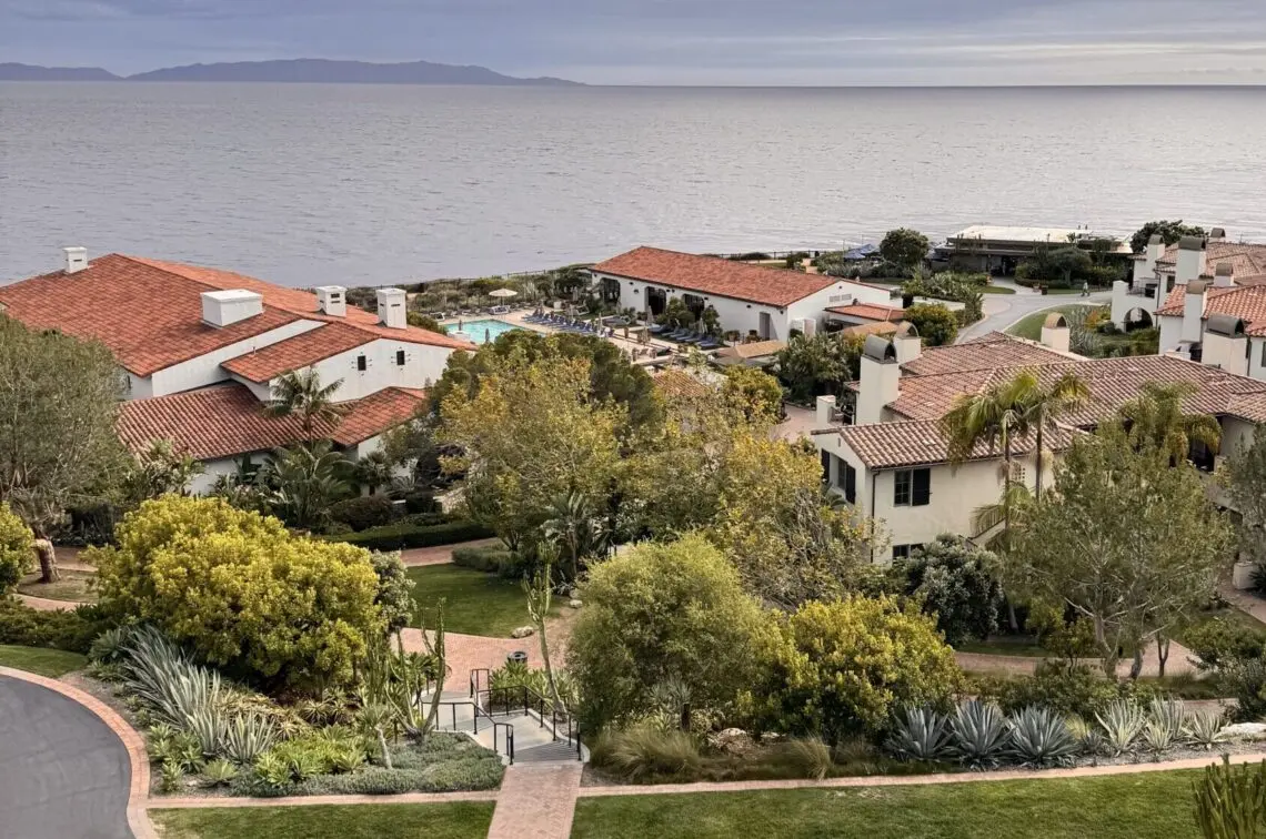 High-angle view of Terranea coastal resort with white buildings and red-tile roofs overlooking the ocean under a cloudy sky.