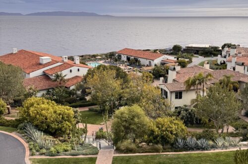 High-angle view of Terranea coastal resort with white buildings and red-tile roofs overlooking the ocean under a cloudy sky.