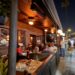 Exterior of Black Market Liquor Bar in Studio City at night with outdoor patio seating and guests dining