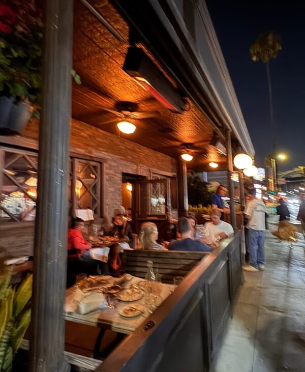 Exterior of Black Market Liquor Bar in Studio City at night with outdoor patio seating and guests dining
