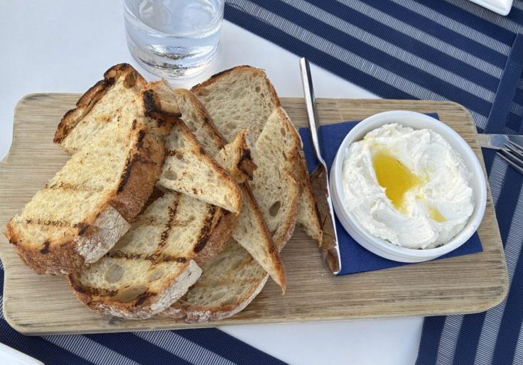 Whipped ricotta dip drizzled with olive oil and topped with Maldon sea salt, served with grilled sourdough on a wooden board at Carbon Beach Club Restaurant at the Malibu Beach Inn