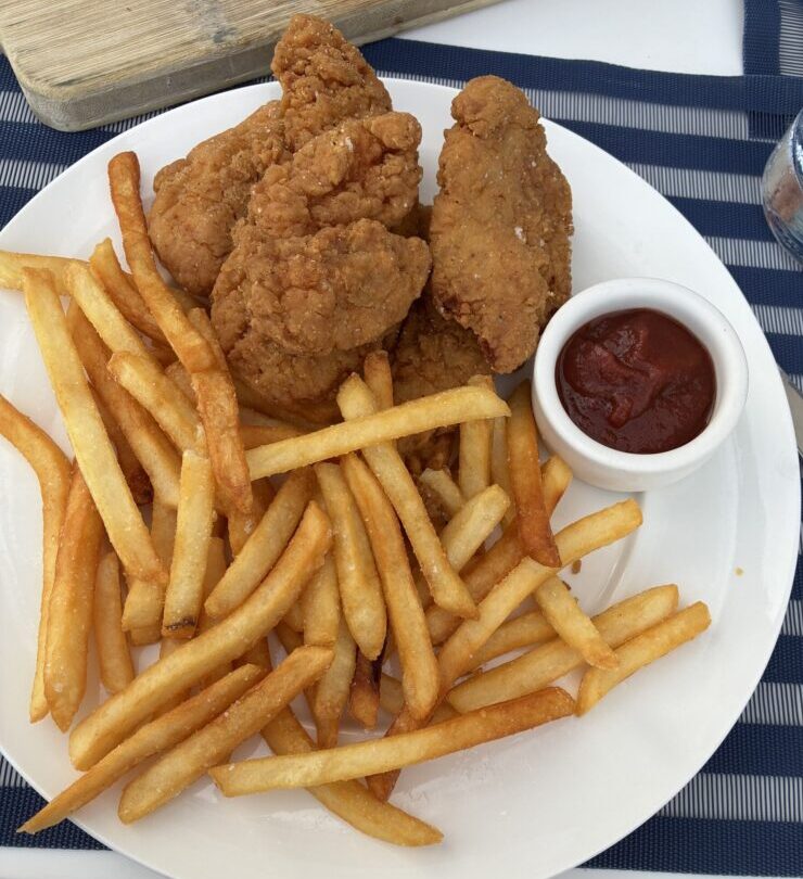Kids' chicken tenders with French fries and a ramekin of ketchup on a white plate at Carbon Beach Club Restaurant at the Malibu Beach Inn