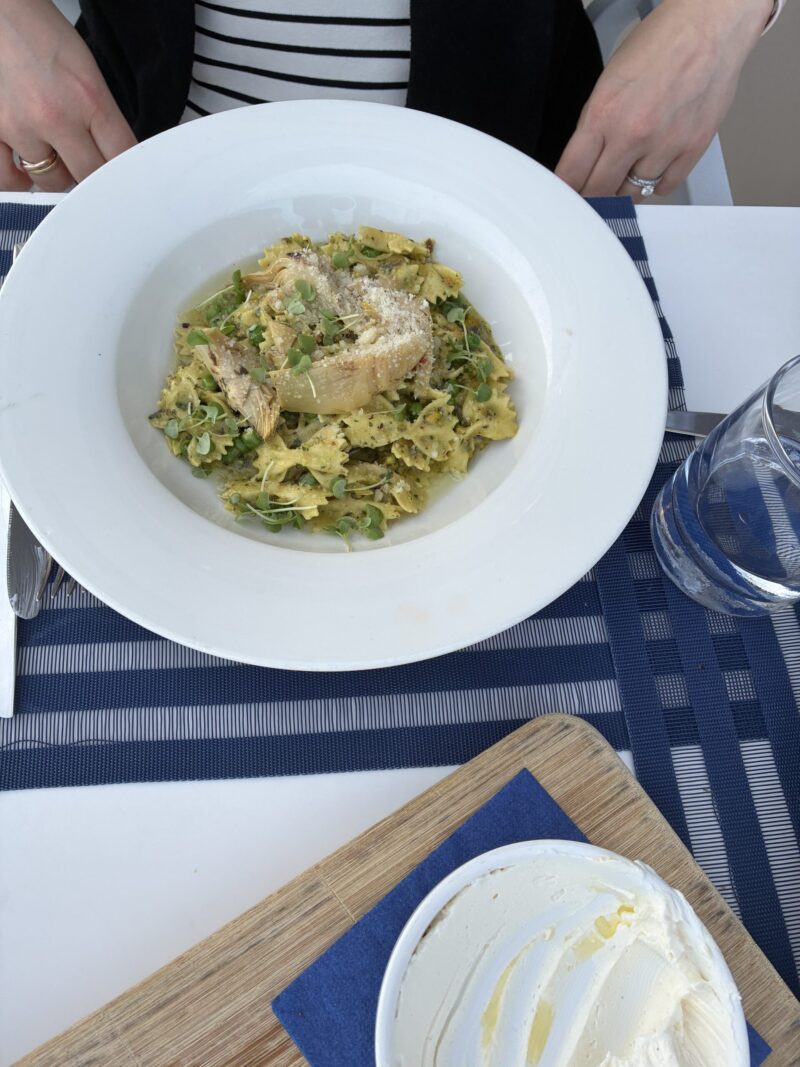 A bowl of farfalle pasta in pistachio pesto with marinated artichokes, English peas, and pecorino romano at Carbon Beach Club Restaurant at the Malibu Beach Inn