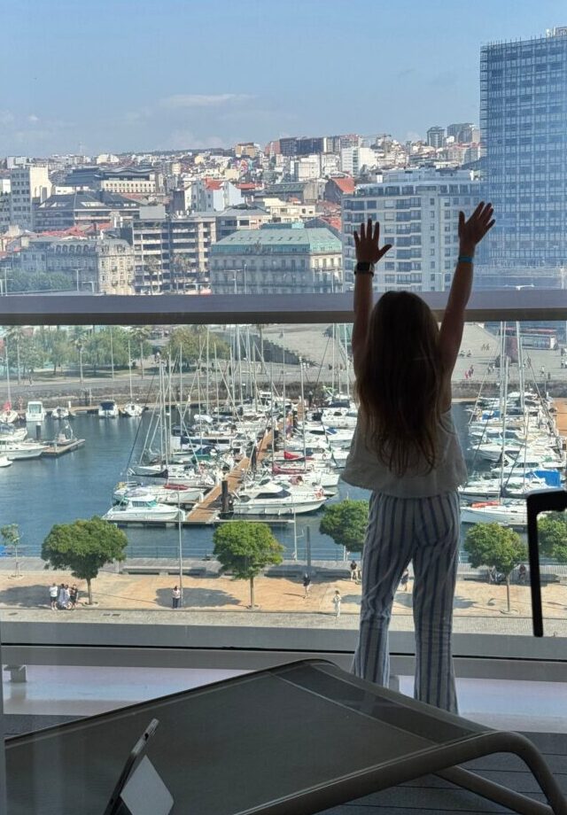 Child looking out the Sky Suite window at the marina in A Coruña, Spain