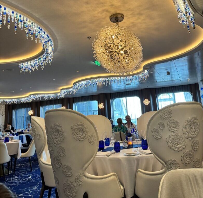 Blu restaurant on Celebrity Apex with white floral chairs and crystal chandeliers