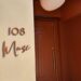 The 108 Muse sign beside the terracotta front door of Muse restaurant in Santa Monica