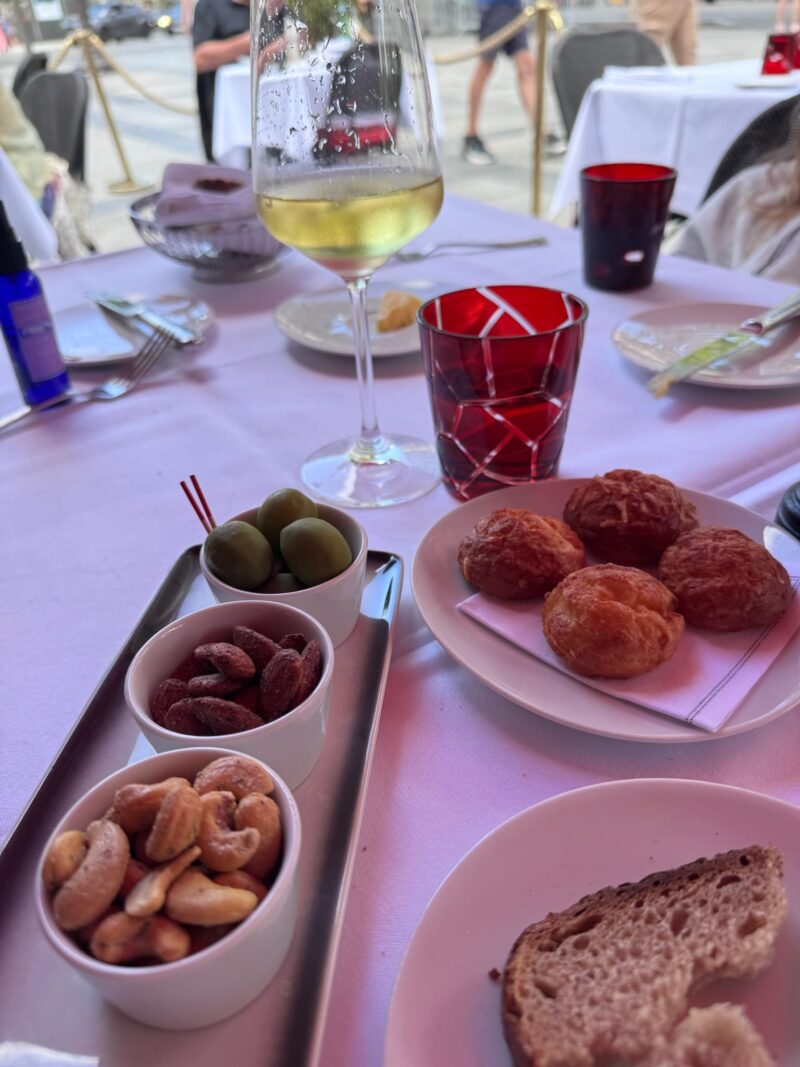 Outdoor table at Fouquet’s in Paris with white wine, olives, nuts, and bread