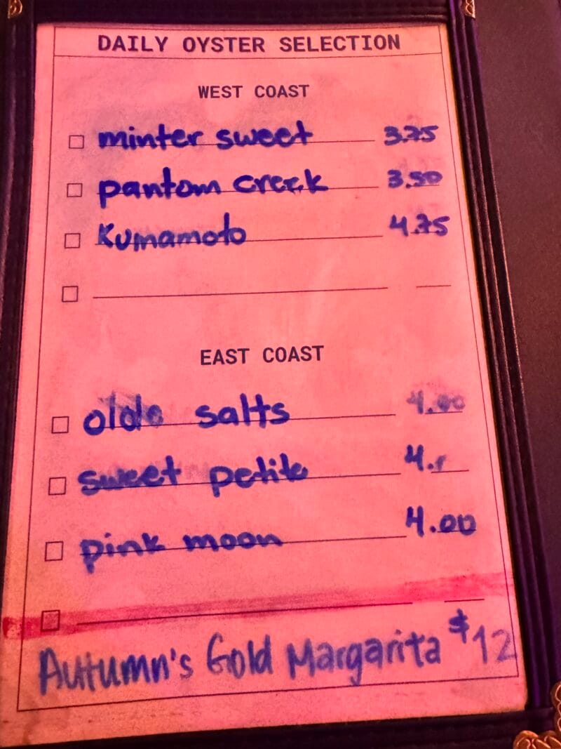 Handwritten Daily Oyster Selection menu at Blue Plate Oysterette, listing West Coast oysters like Minter Sweet, Phantom Creek, and Kumamoto, and East Coast oysters like Olde Salts, Sweet Petite, and Pink Moon