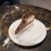 A rich slice of chocolate cheesecake drizzled with chocolate sauce
