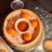Bamboo steamer basket of orange dumplings topped with red tobiko around a bowl of chili oil dipping sauce