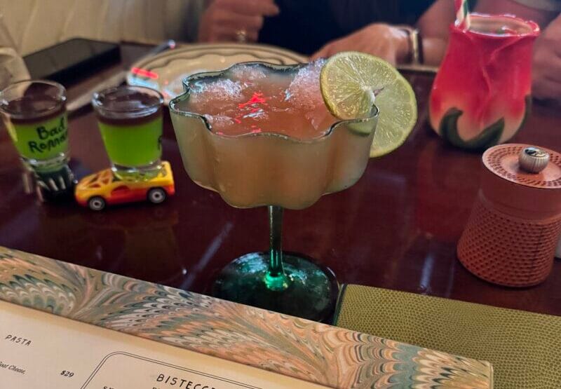 A Tequila Granita served in a frosted glass with a lime wheel, green Lamborghini shots on toy cars, and a Strawberry Sbagliato at Bad Roman Beverly Hills.