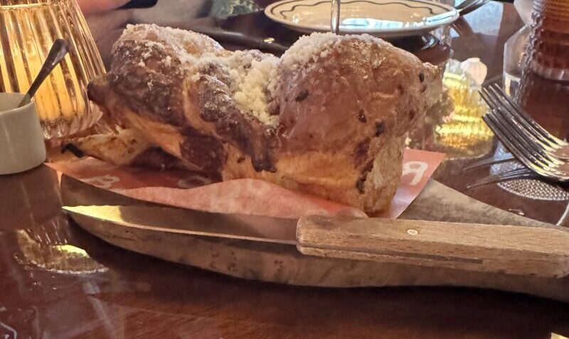 A torn-open loaf of Roasted Garlic Babka on a wooden board at Bad Roman Beverly Hills.