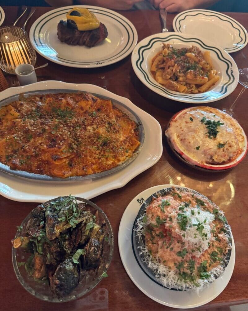 Main courses at Bad Roman including Chicken Scarpariello Rigatoni, the Filetto with Cacio e Pepe Raviolo, Spicy Brussels Sprouts, B'B Paccheri, chicken parm, and Filet Mignon Meatballs.