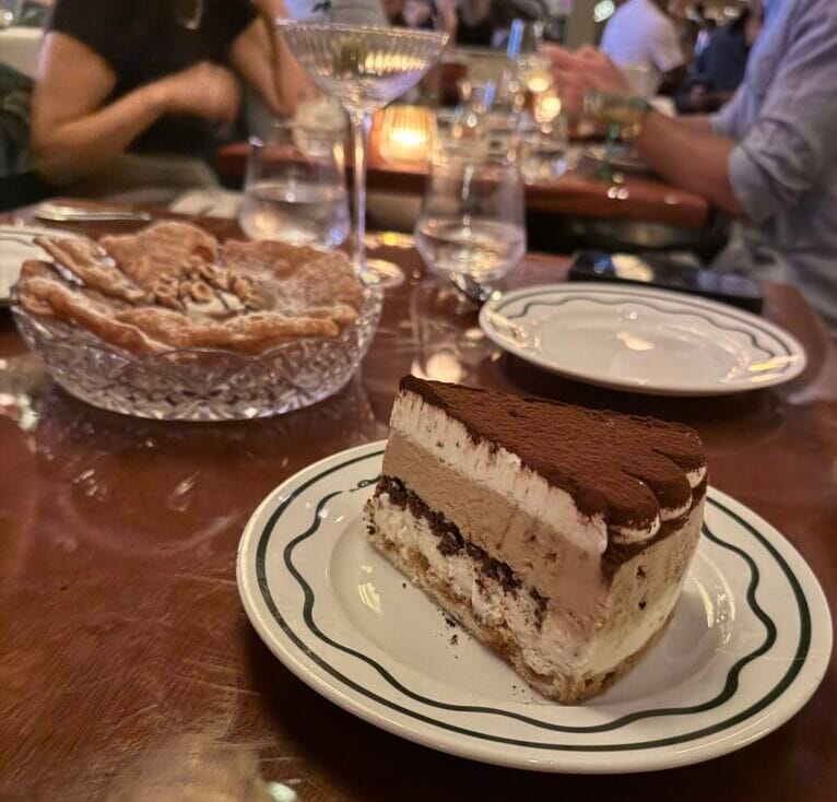 A slice of Tiramisu Ice Cream Cake dusted with cocoa next to the Hazelnut Cannoli Sbagliati at Bad Roman.