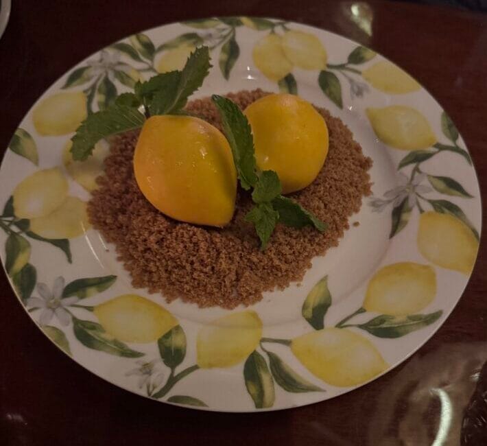 The Lemon Cheesecake at Bad Roman Beverly Hills, shaped like two whole lemons on graham streusel with mint, served on a lemon-print plate.