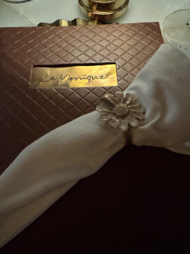 Gold-plated menu cover with a linen napkin and silver flower napkin ring
