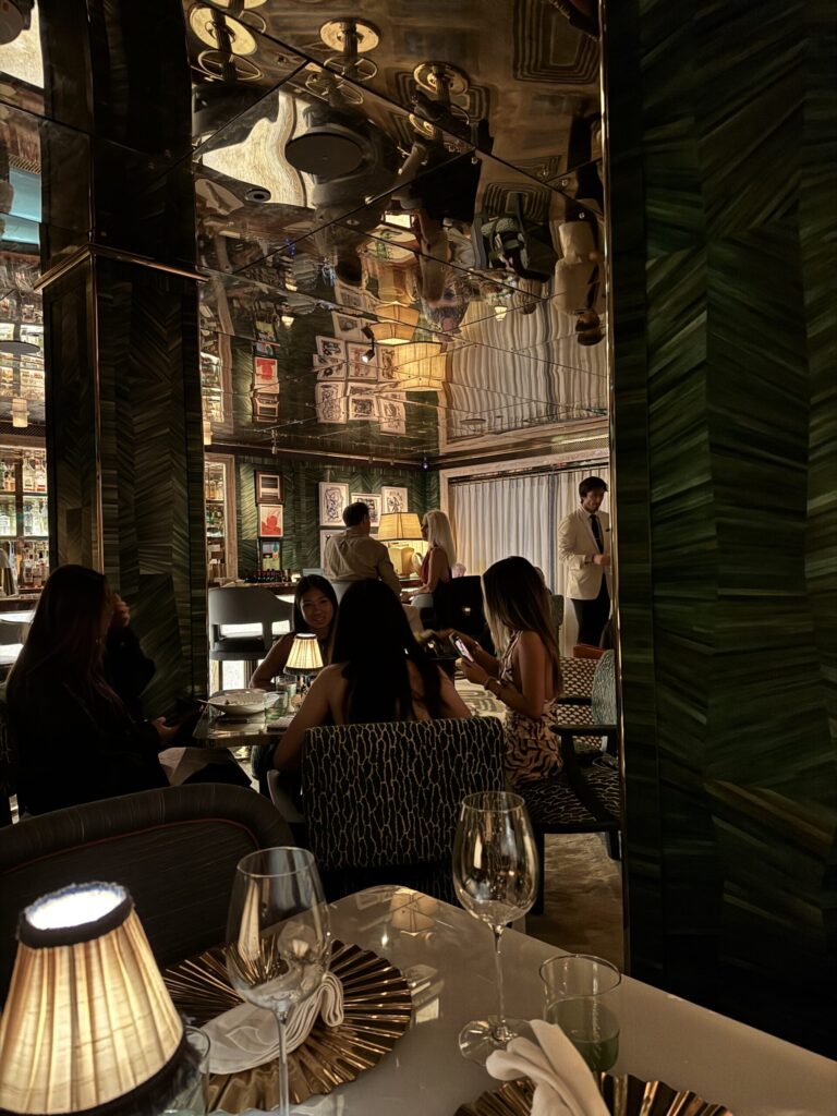 Dining room at La Monique Santa Monica with mirrored ceiling, green walls, and table lamps
