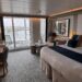 The Celebrity Edge-class Sky Suite bedroom with a plush bed and floor-to-ceiling views out to the balcony and rooftop.
