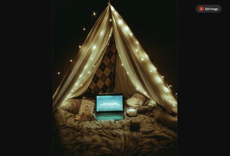 A cozy blanket fort made of white sheets glowing with warm fairy lights, set up for a sleepover wind-down (stock photo, used for illustration)