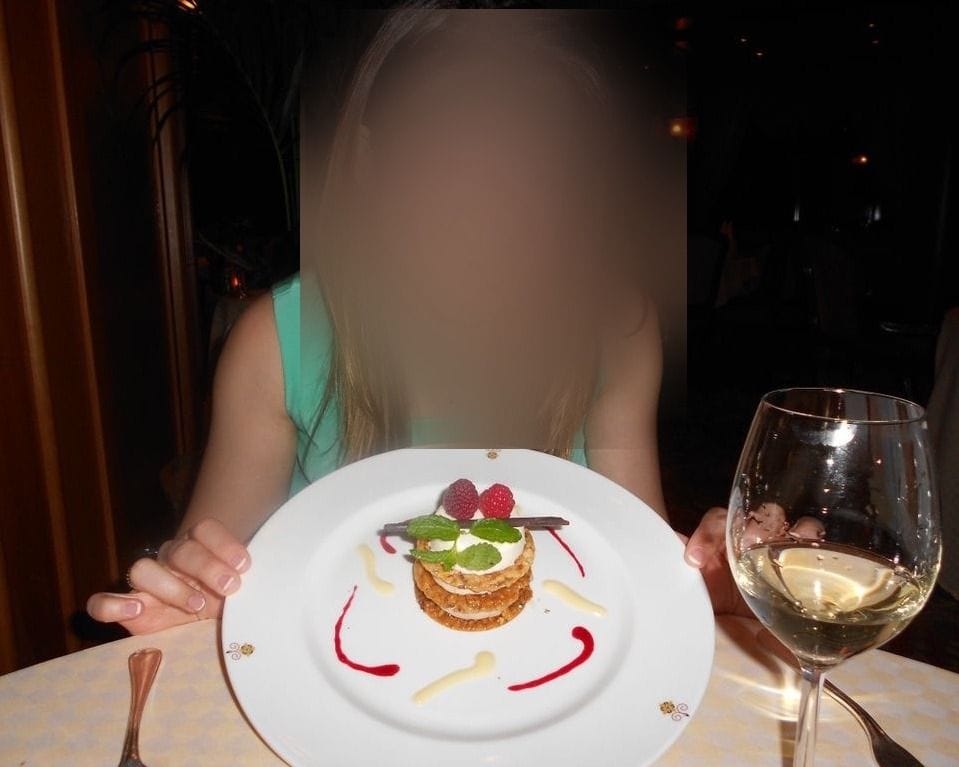 A layered pastry dessert with fresh raspberries and mint, drizzled with raspberry and vanilla sauce, at a cruise ship specialty restaurant.