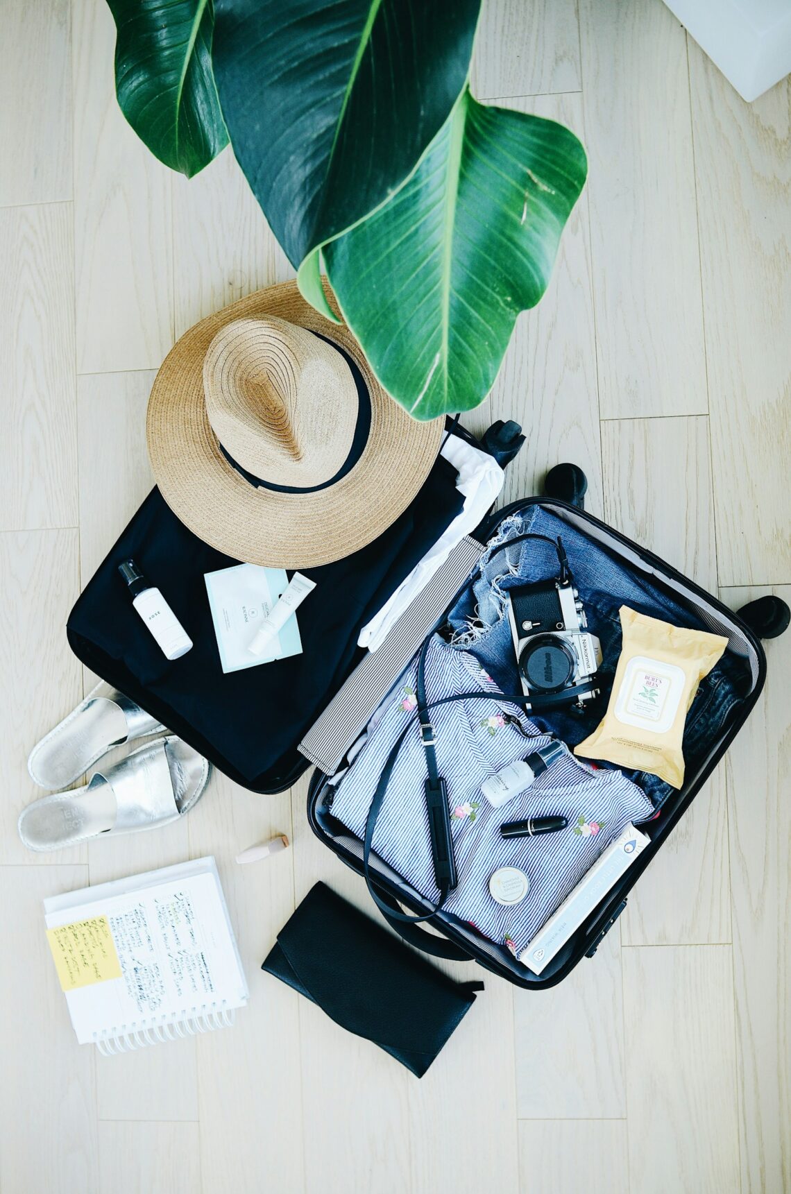 An open suitcase mid-packing for a cruise, with clothes, a sun hat, and travel essentials neatly organized