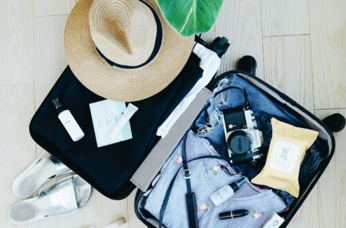 An open suitcase mid-packing for a cruise, with clothes, a sun hat, and travel essentials neatly organized
