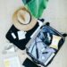 An open suitcase mid-packing for a cruise, with clothes, a sun hat, and travel essentials neatly organized